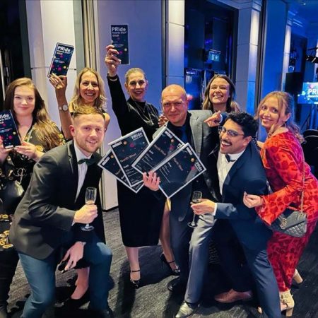 Eight staff members displaying an award won at the CIPR North West PRide Awards.