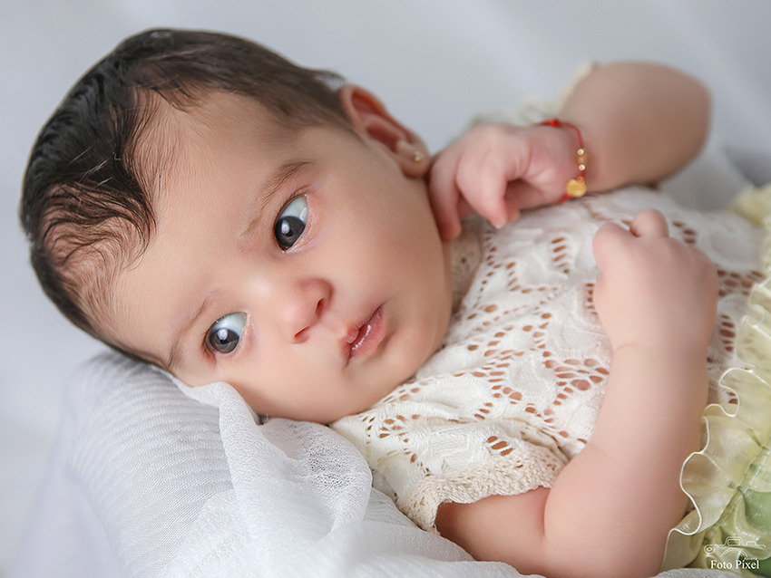 Image of a new born baby girl, lying on her back with eyes open.